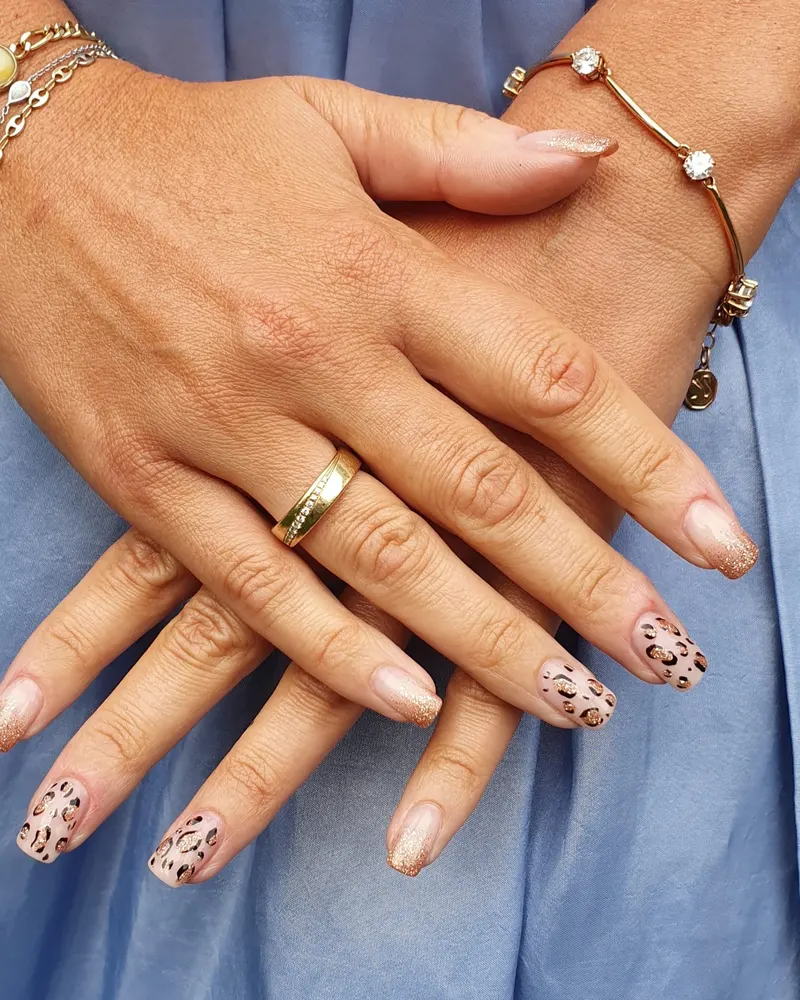 Nude-Nägel mit Leoparden-Nail-Art, Hände auf blauem Stoff